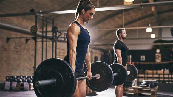 Female and male athletes performing deadlifts at a CrossFit gym
