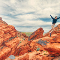girl jumping from vibrant orange rock to another rock / myHMB article How the Active Nutrition Market is Expanding for Consumers Needs