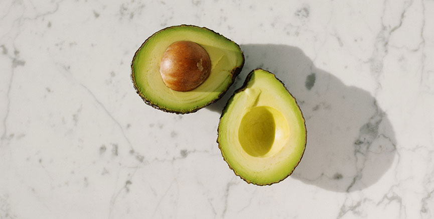 Avocado sliced open on countertop / Carbs vs. Fats myHMB blog