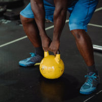 man in a gym lifting a yellow kettbell off the floor / myHMB blog Fitness Gear Must-Haves by Jennifer Dietrick