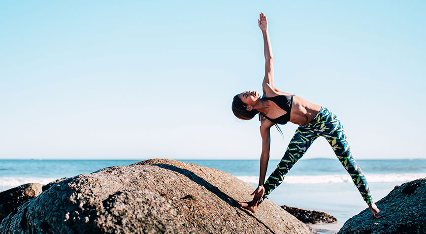 woman outdoors performing yoga on rocks