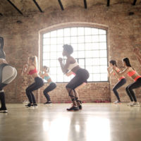 women in a fitness group class all performing a bodyweight squat / myHMB Blog back to the basics - the squat by Carissa Johnson