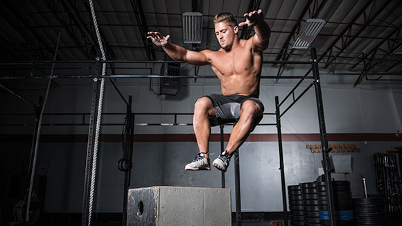 Sam Dancer in a Crossfit gym performing a box jump