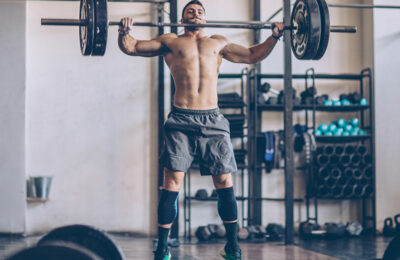 male athlete in a crossfit gym snatching a barbell