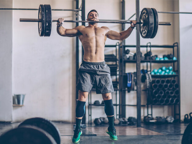 male athlete in a crossfit gym snatching a barbell
