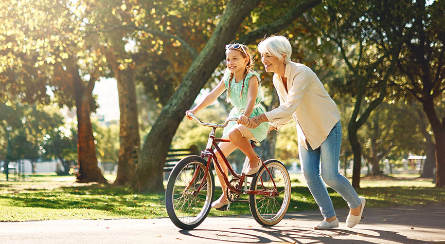 grandmother helping her granddaughter ride a bike