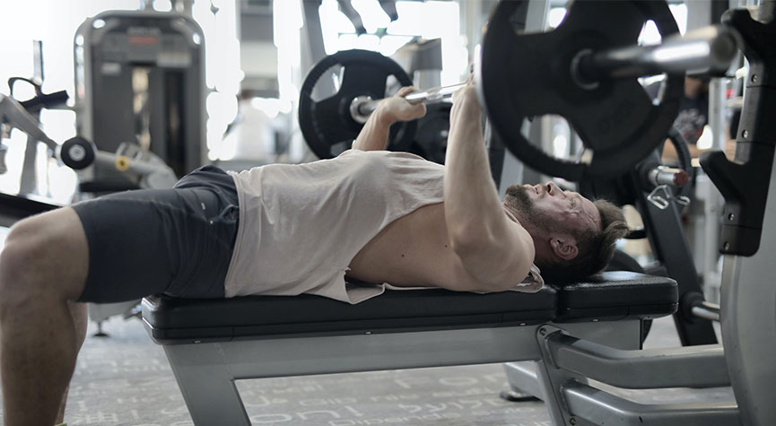 athletic male performing a bench press in a gym