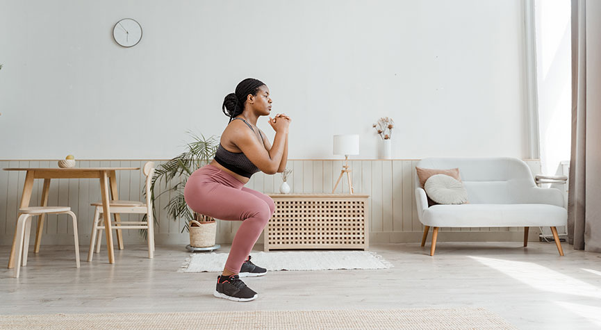 woman in home doing a workout - performing air squat
