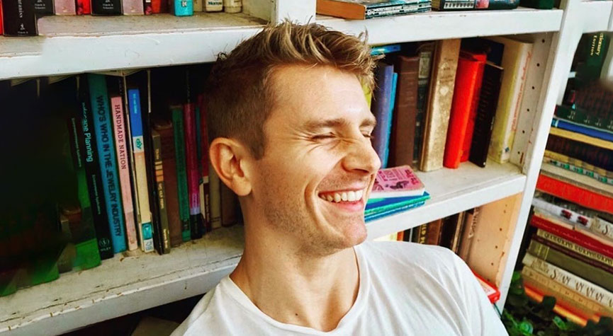 Bryce Smith sitting against a book case and smiling