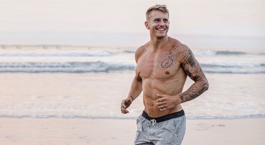 Bryce Smith on the beach running by the ocean and smiling