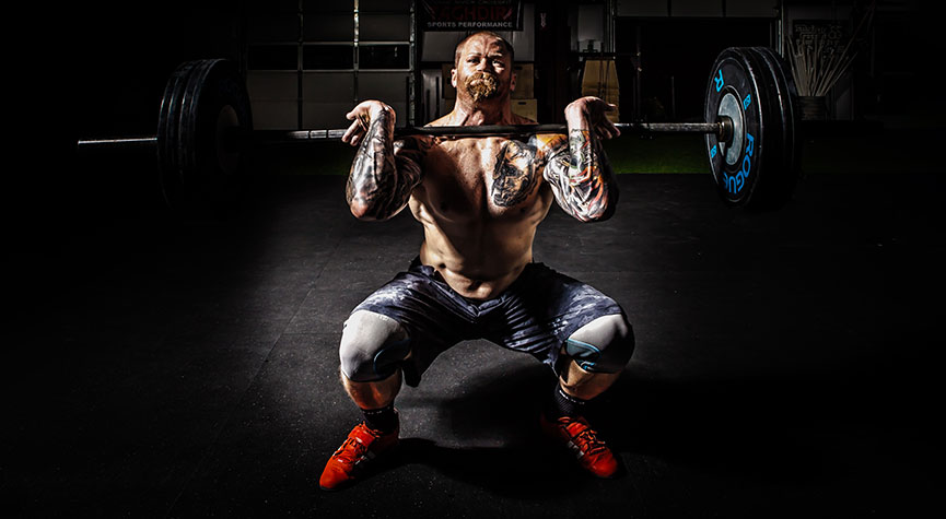 athletic male in a gym performing a front squat with a barbell