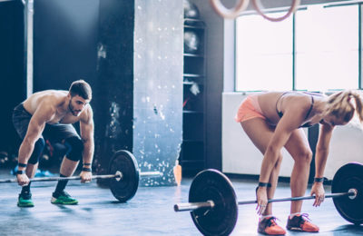 a male and female athlete gripping barbells with weights in a CrossFit gym about to start a Metcoon | myHMB blog Why You Aren’t Seeing Results from Your Workouts: Part 2 by Korey Van Wyk