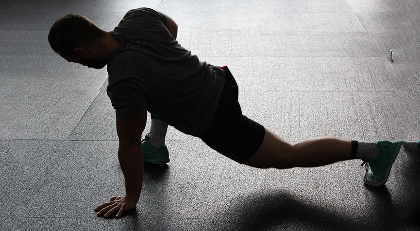 male athlete in a gym doing a spiderman stretch