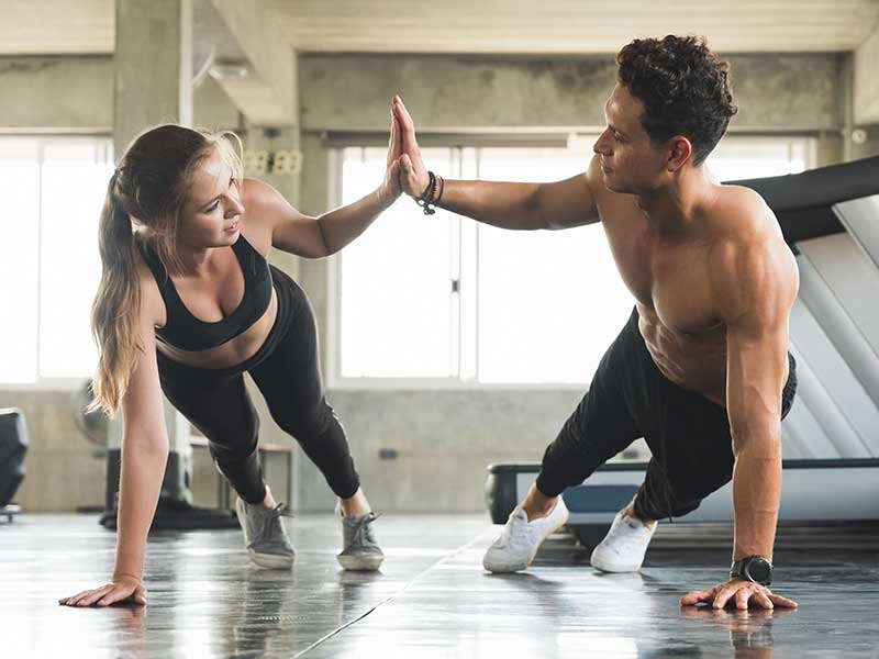 a gym setting with a couple high giving in a plank position